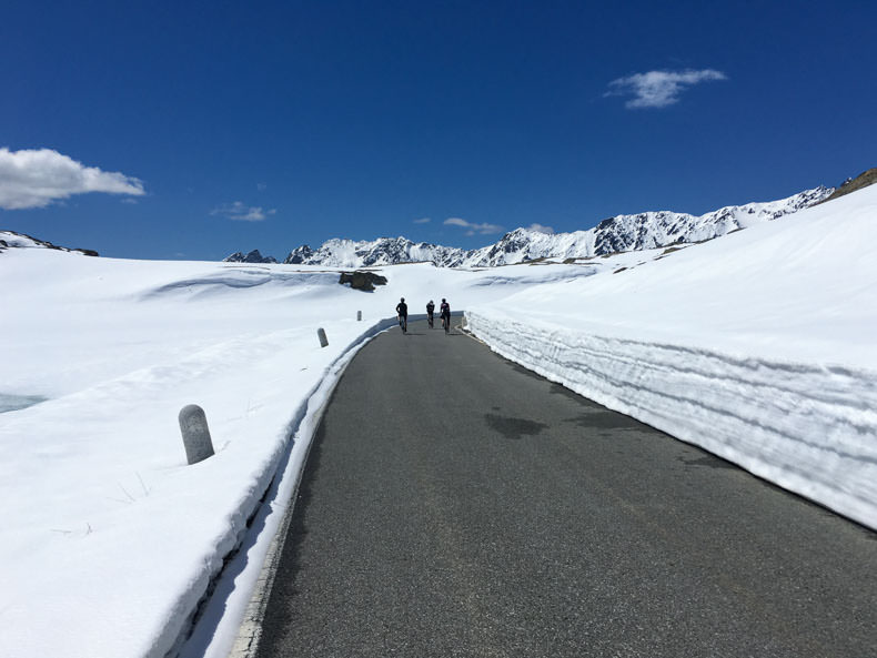 A group of cyclists riding through the snow to the top of Passo Gavia