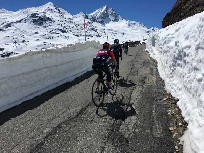 Cyclist riding between walls of snow on Gavia