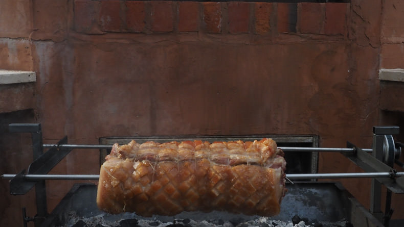 a slow cooked porchetta over charcoal