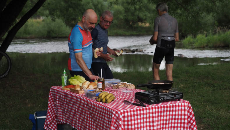 A group of cyclists having lunch by the river