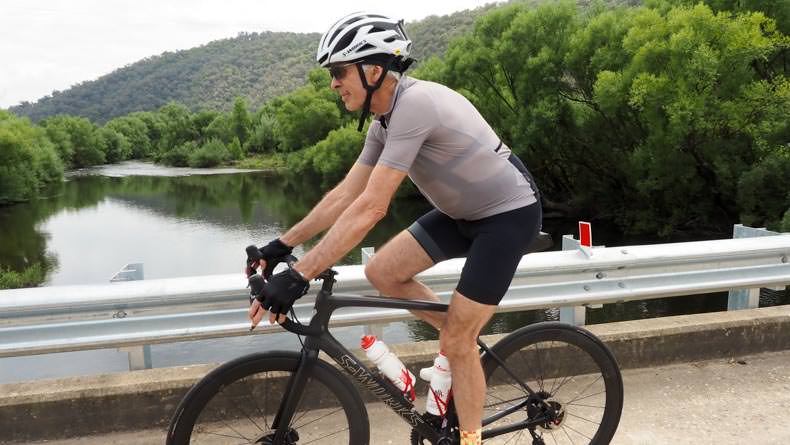 a man cycling over a bridge in the country